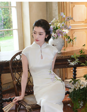 Seated view of the white iris cheongsam and smooth satin skirt