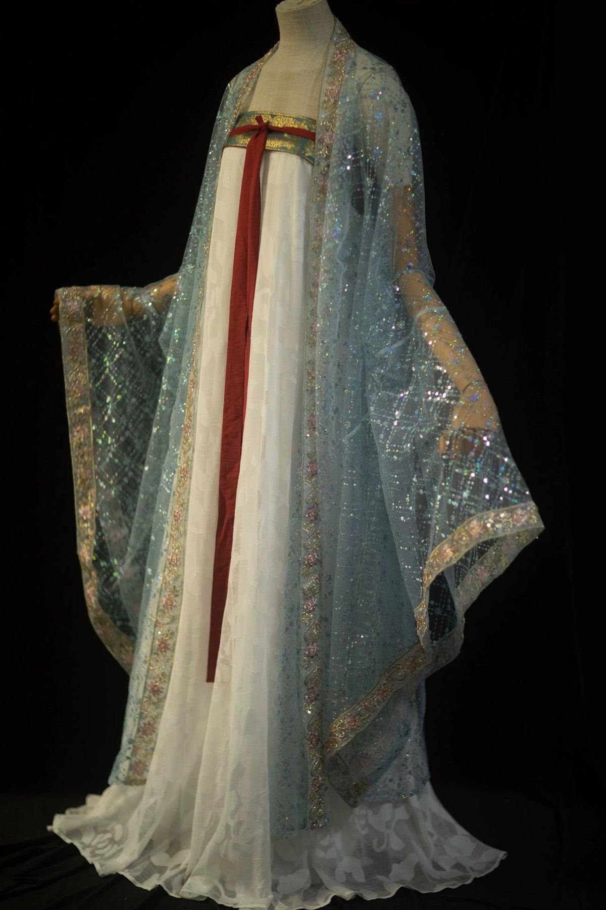 Blue sequin robe displayed over a white skirt with the wide sleeves spread out