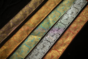 Five decorative brocade sash fabrics in purple, orange, blue, black and red colorways