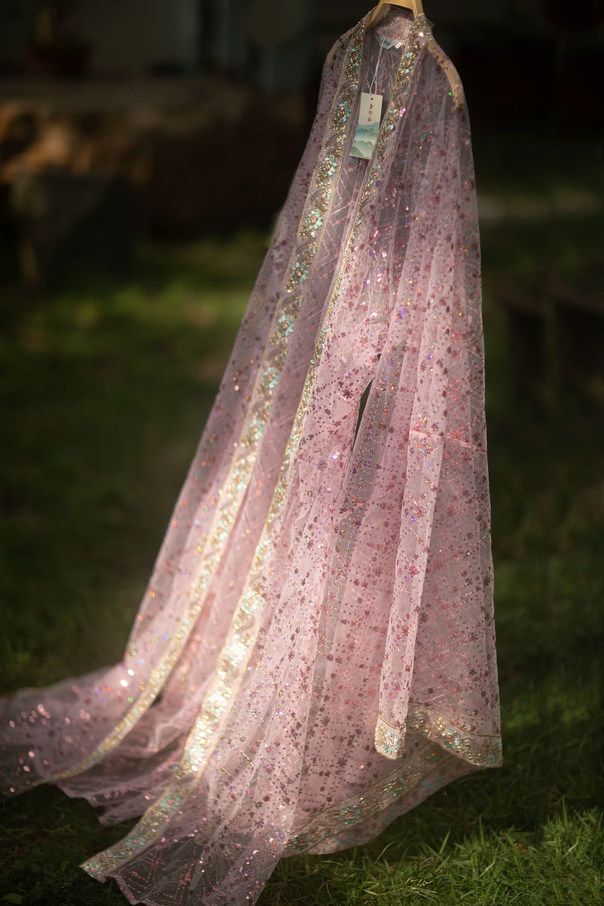 Pink sequin Hanfu robe displayed alone on a hanger with its long trailing panels