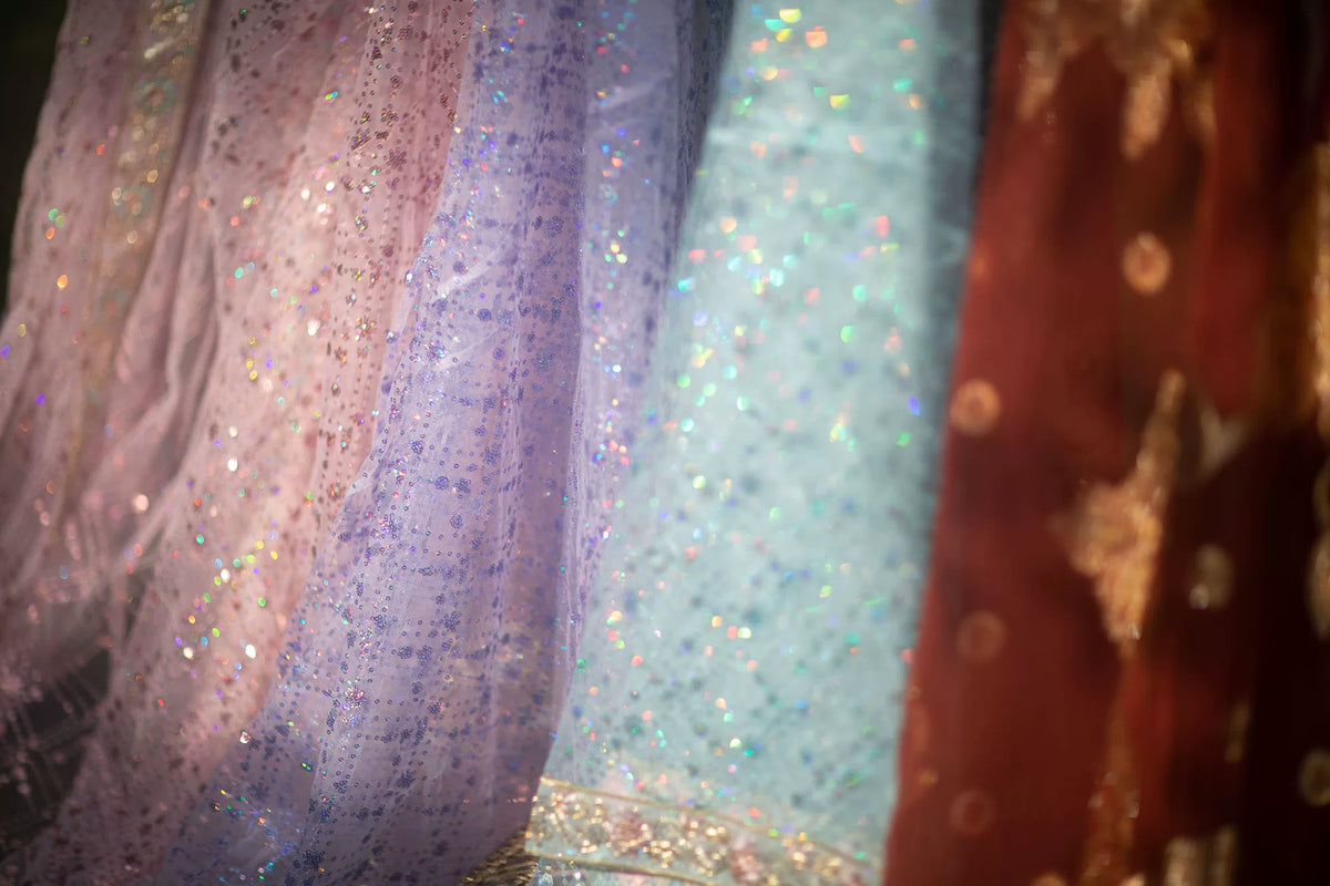 Pink, purple and blue sequin fabric panels shown together in a close-up color comparison