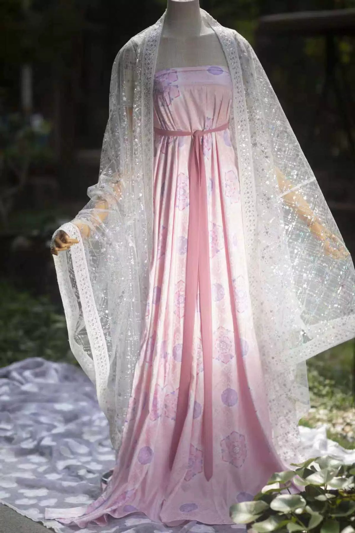 White pearl-sheen sequin robe styled over a pink skirt on an outdoor mannequin