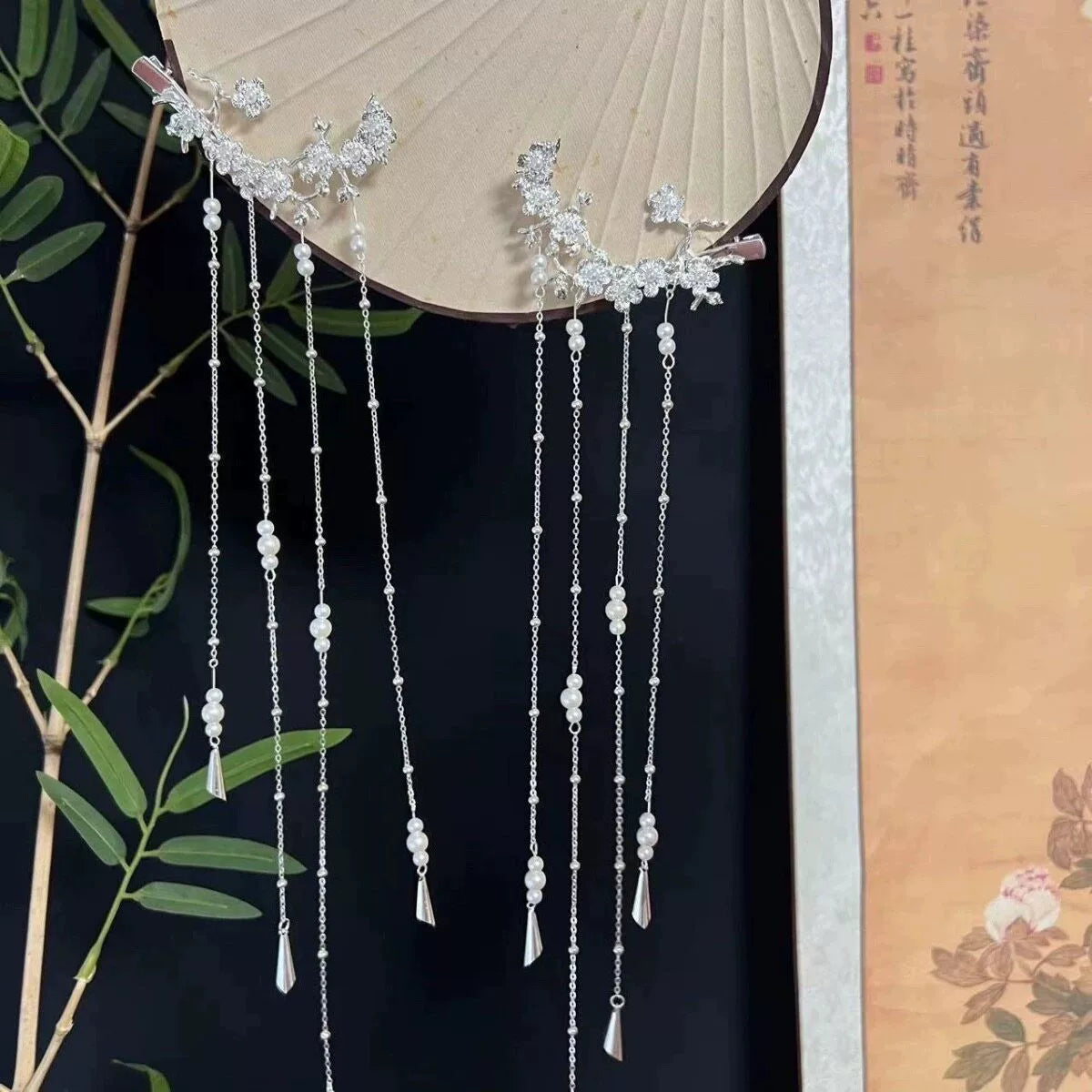 Pair of long tassel hair ornaments displayed on a fan