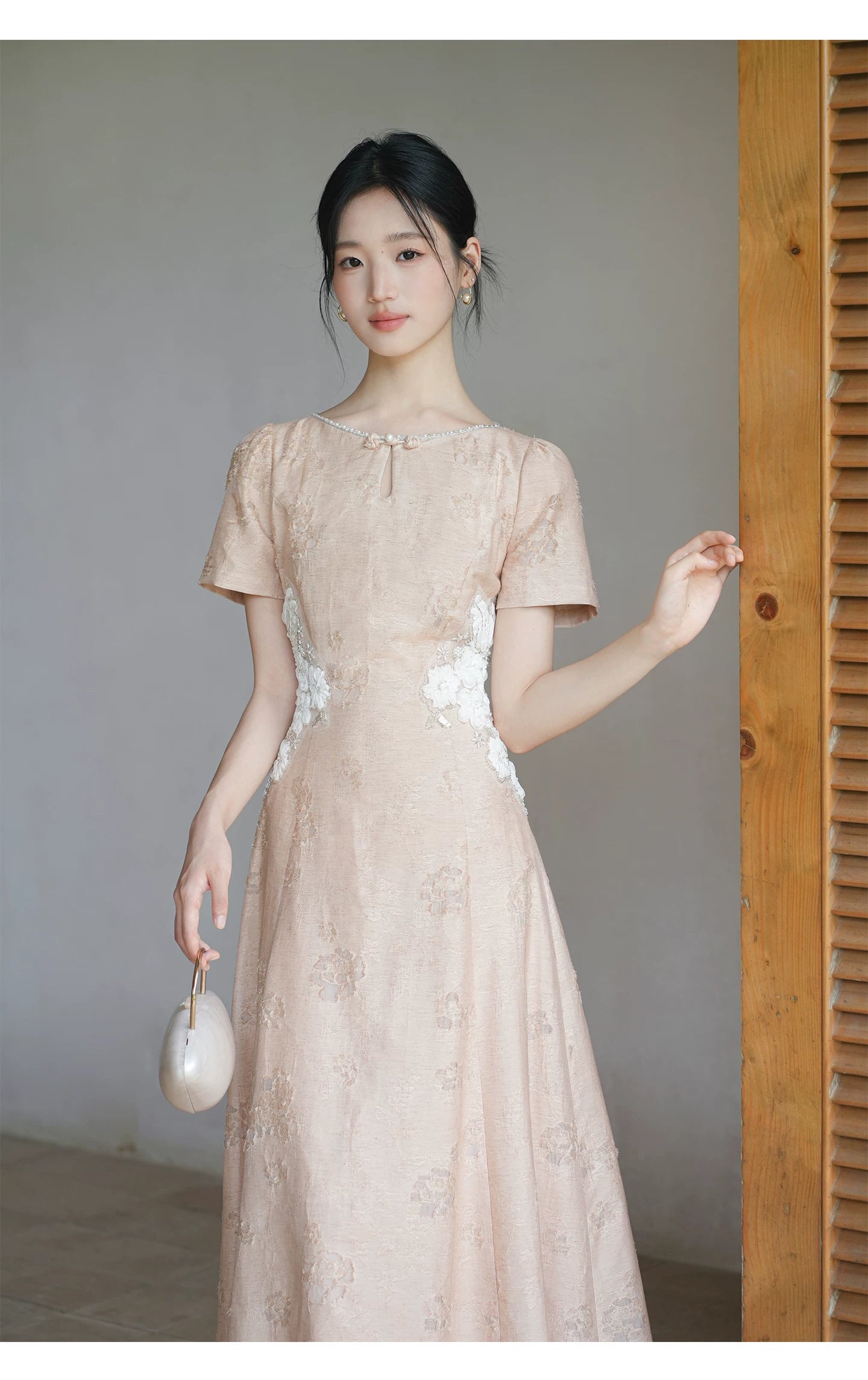 Design view of the Soft Sand Pink floral applique cheongsam dress, highlighting pearl neckline, floral waist applique and long A-line silhouette.