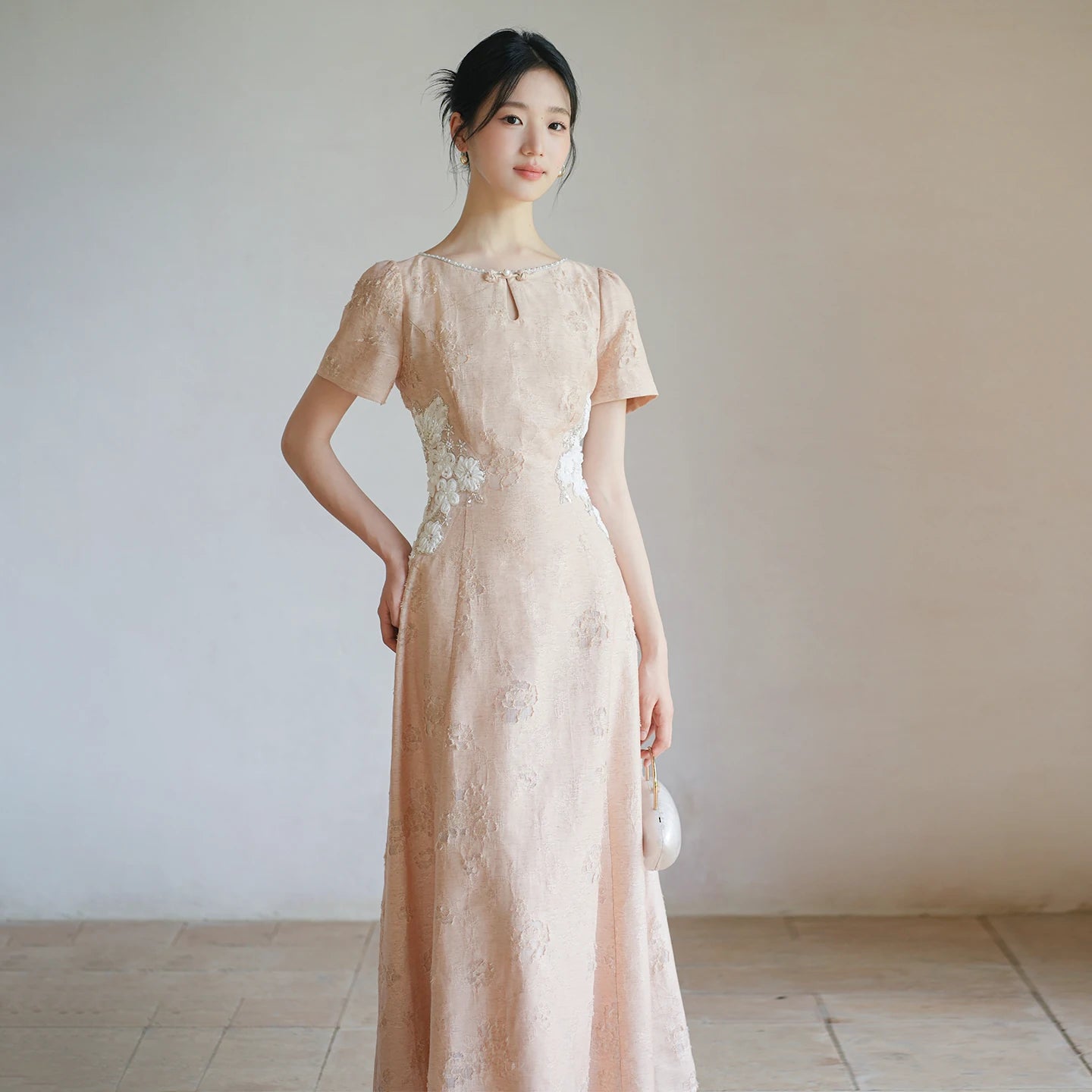 Soft Sand Pink floral applique cheongsam dress shown as a polished modern pink qipao dress, highlighting pearl neckline, floral waist applique and long A-line silhouette.