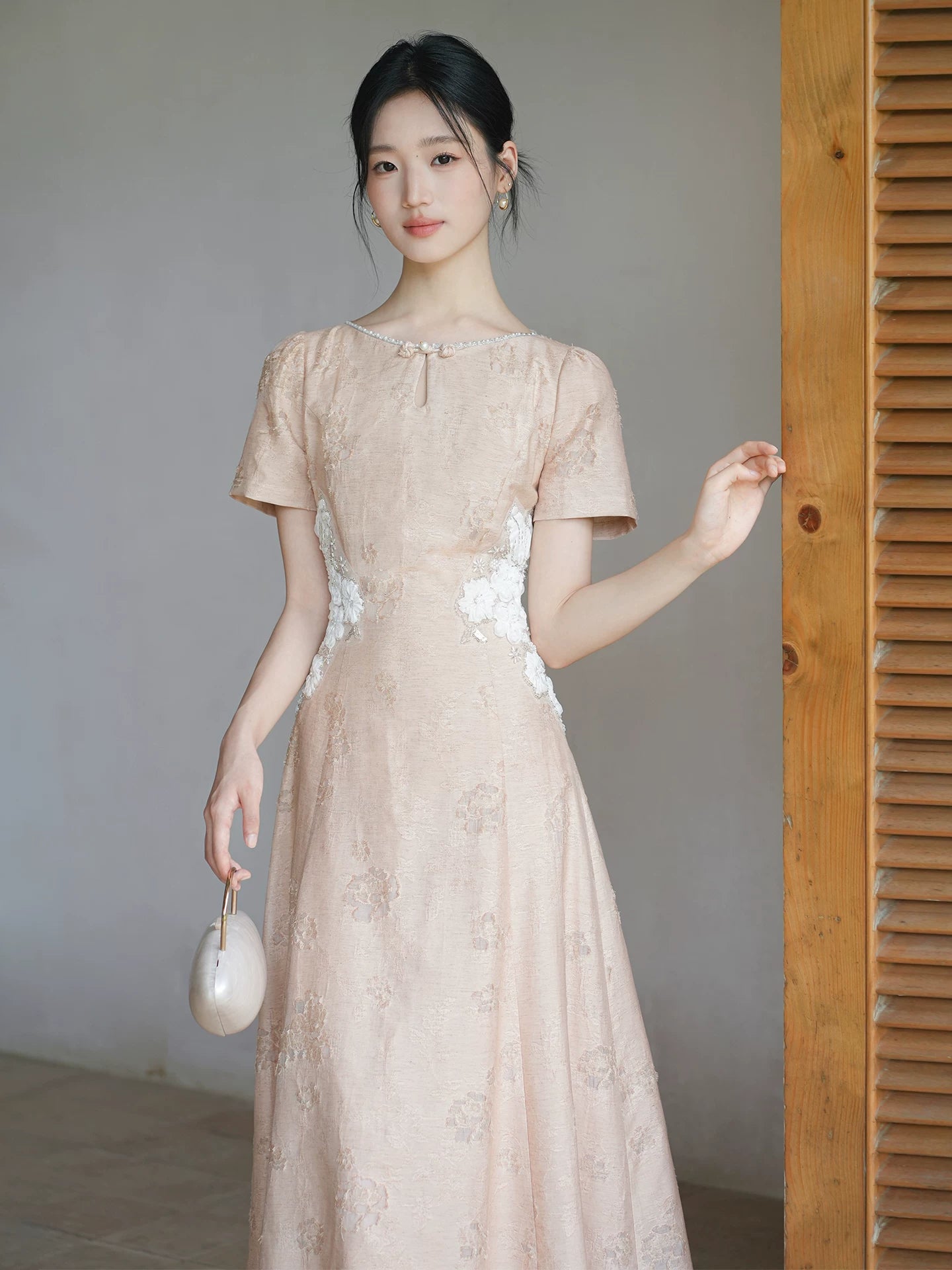 Front styling view of the Soft Sand Pink floral applique cheongsam dress, with pearl neckline, floral waist applique and long A-line silhouette.
