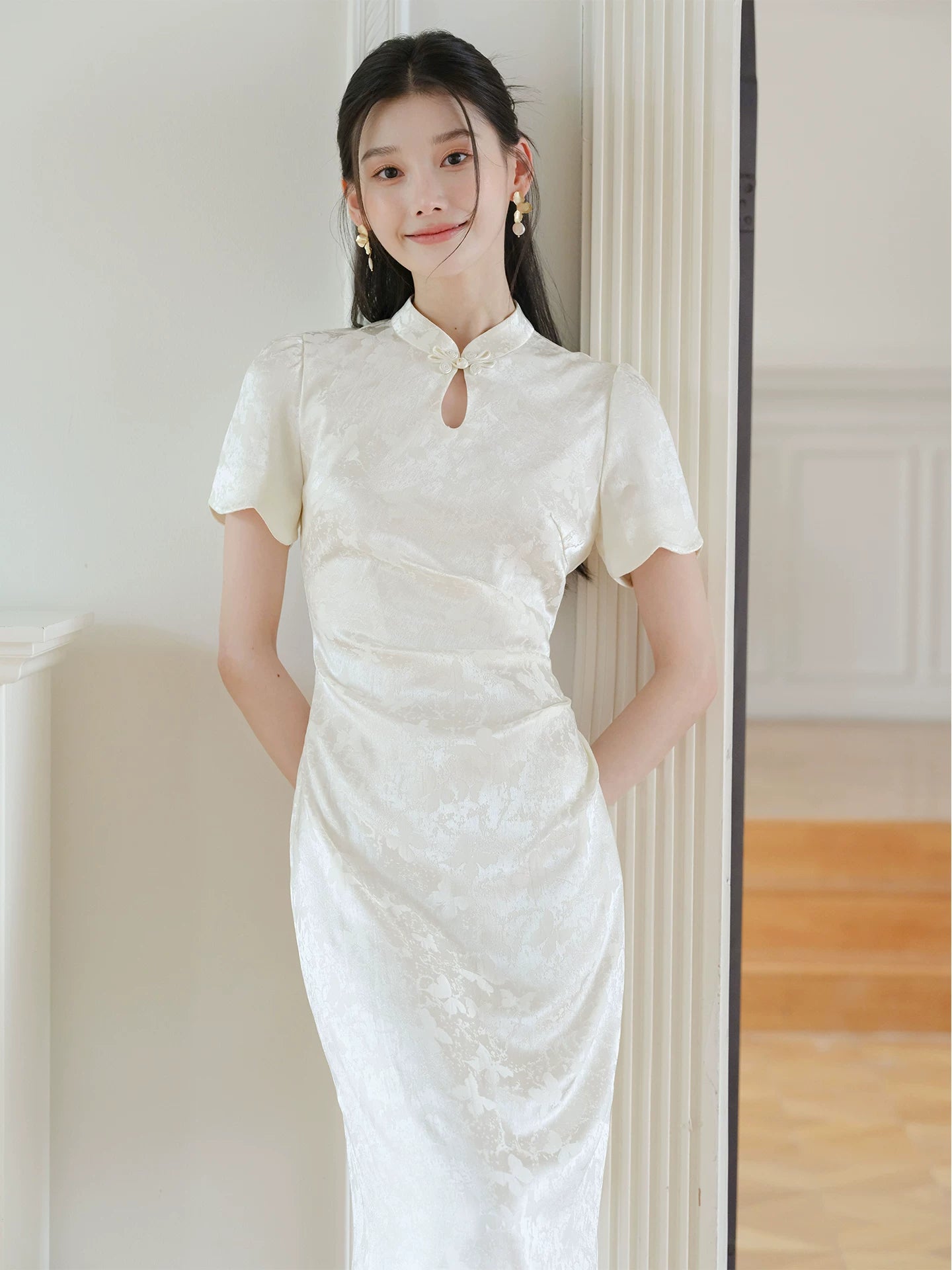 Design view of the Soft White jacquard pleated qipao dress, highlighting subtle jacquard, fitted waist, front pleats and keyhole mandarin collar.