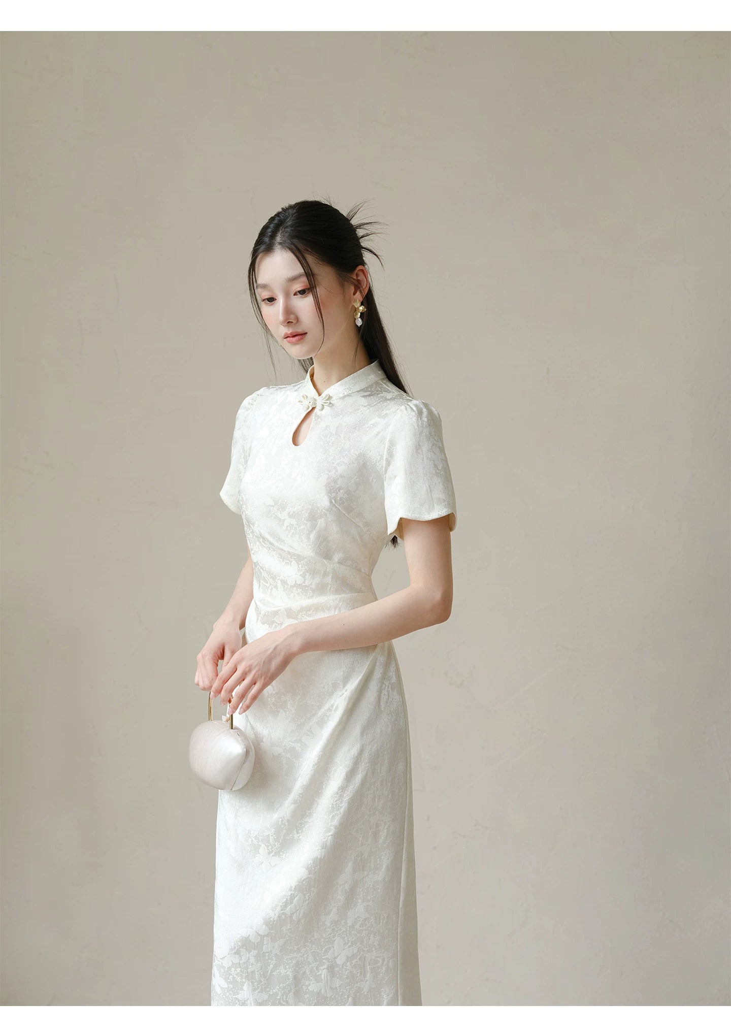 Additional styling view of the Soft White jacquard pleated qipao dress, showing the garment's shape, texture and finish.