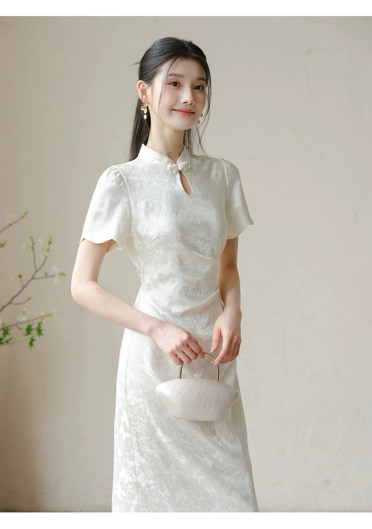 Front styling view of the Soft White jacquard pleated qipao dress, with subtle jacquard, fitted waist, front pleats and keyhole mandarin collar.