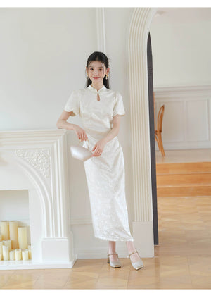 Design view of the Soft White jacquard pleated qipao dress, highlighting subtle jacquard, fitted waist, front pleats and keyhole mandarin collar.