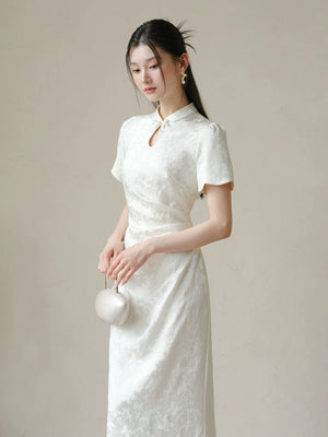 Soft White jacquard pleated qipao dress styled to show its fit and drape, including subtle jacquard, fitted waist, front pleats and keyhole mandarin collar.
