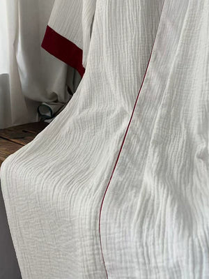 Front product view of the white cotton gauze crossover robe with red trim