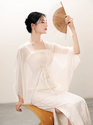 Front styling view of the White embroidered slip dress and sheer outer layer, with embroidered slip dress, translucent outer layer and soft layered drape.
