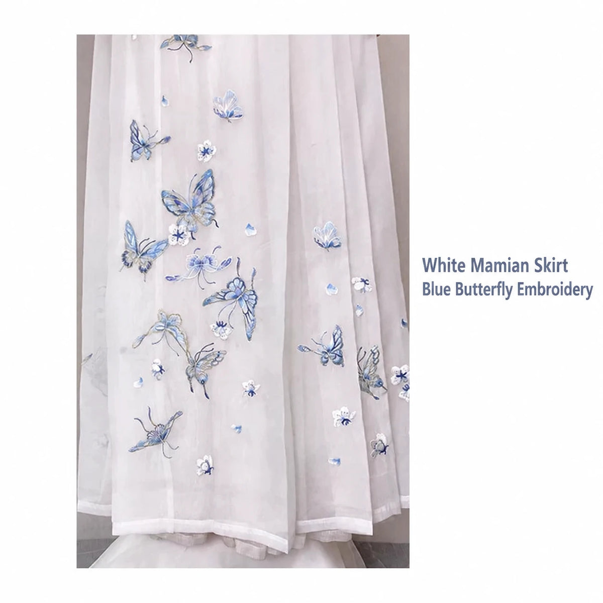 White mamian skirt close-up showing blue butterfly embroidery and the layered appearance of the sheer fabric