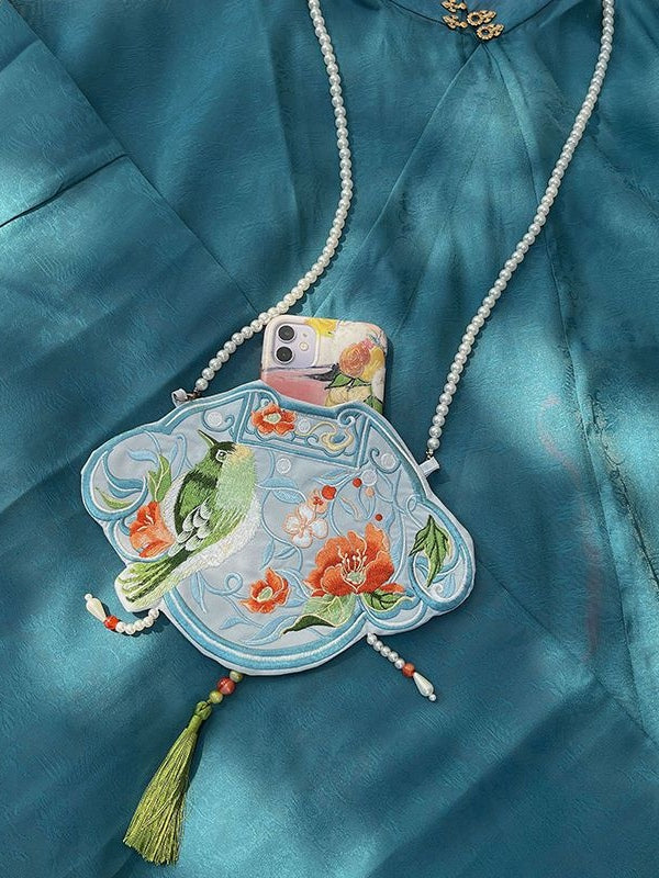 A beautiful blue Hanfu bag featuring intricate embroidery in a traditional Chinese pattern. The bag is made of high-quality materials and has a spacious interior, making it the perfect accessory for everyday use or special events. The blue color adds a pop of color to any outfit and showcases the fusion of traditional Chinese culture with modern fashion.